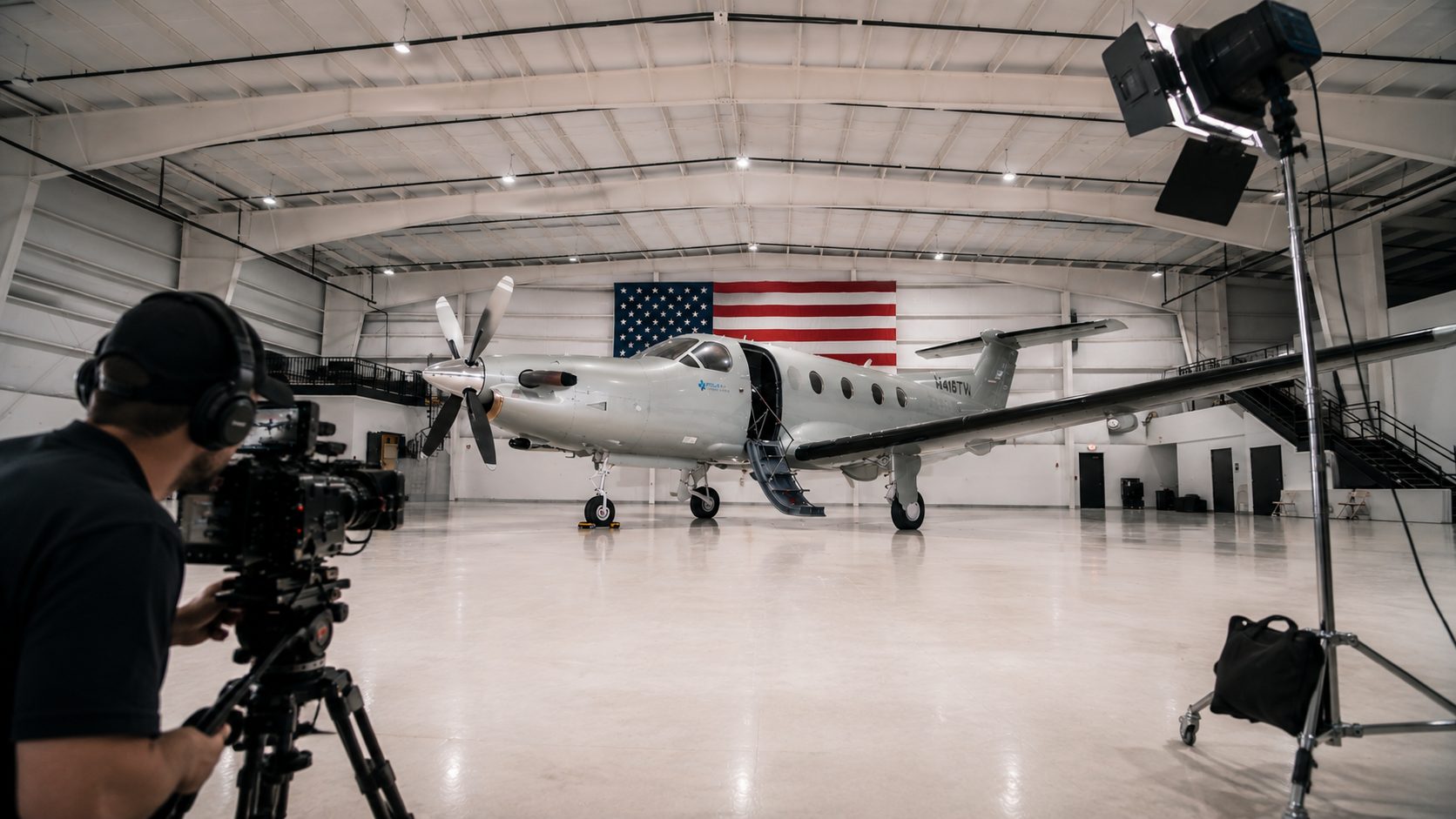 Cinematographer filming a Pilatus PC-12 inside a lit hangar